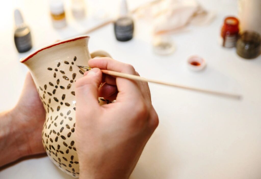 photo of artist painting pottery